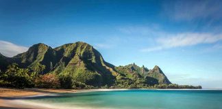 Beach with mountains and clear blue water.