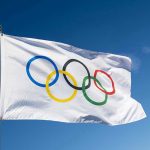 Canada Chokes—USA Claims Epic Gold Olympic flag waving against clear blue sky.
