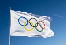 Canada Chokes—USA Claims Epic Gold Olympic flag waving against clear blue sky.