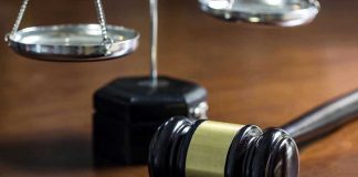 Gavel and scales of justice on wooden table.