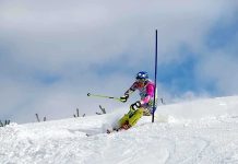 Athlete skiing down a snowy slope around a slalom pole