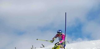 Athlete skiing down a snowy slope around a slalom pole