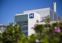 Trump Drug Transparency Move Shakes Hospitals Modern hospital building with a prominent H sign against a clear blue sky