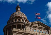 Ex-Yankees Star Crushes Texas Political Scene Building dome with US and Texas flags, blue sky.