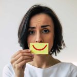 Harvard Study DESTROYS Everything About Career Success Woman holding smiley face card over mouth