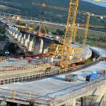 OSHA’s New Heat Rule: Game Changer! Construction of a large bridge with cranes and machinery in operation