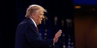 Person speaking at a podium with hand raised