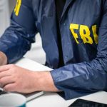 Mar-a-Lago Raid: FBI Objections IGNORED! Person in FBI jacket typing on a laptop.