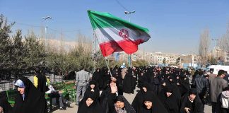 Hormuz Shock: Iran’s New Offer Group of women in black attire marching with an Iranian flag