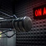 Microphone in soundproof studio with On Air sign.