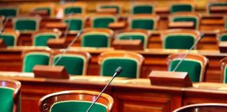 AI in Schools: Gaining Control or Losing Focus? Empty legislative chamber with green upholstered chairs and wooden desks