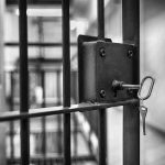 Jail cell door with key in lock.