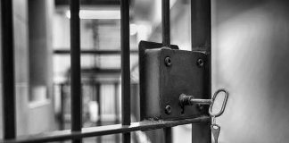 Jail cell door with key in lock.