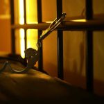 Open handcuffs hanging in dimly lit cell