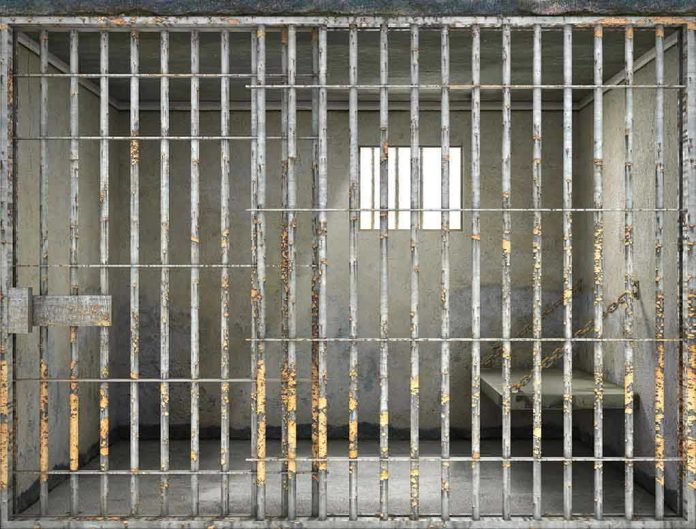 Empty rusty prison cell with a small window.