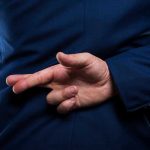 Person crossing fingers behind their back in suit