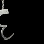 Single open handcuff against a black background.