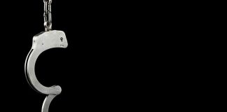 Single open handcuff against a black background.