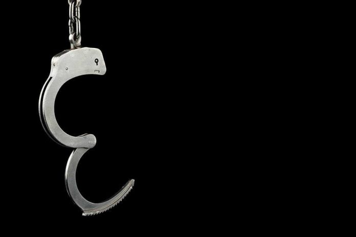 Single open handcuff against a black background.