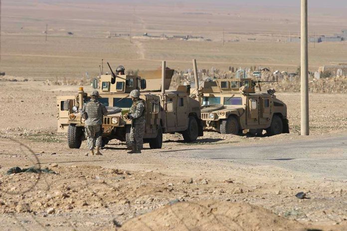 76580419-1 Soldiers standing near armored vehicles in desert terrain.