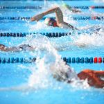 Swimmers competing in a pool, creating splashes of water