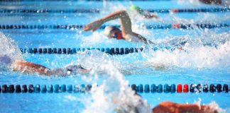 Swimmers competing in a pool, creating splashes of water