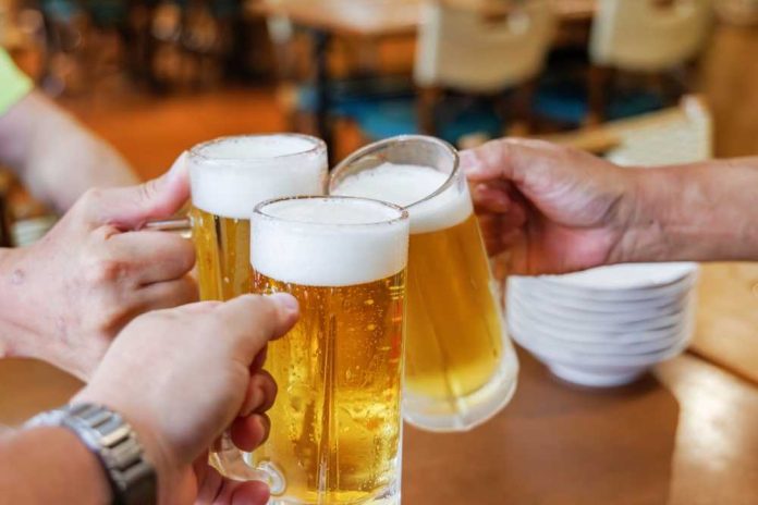 Three hands clinking frothy beer mugs