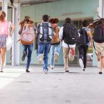 Children running with backpacks outside a school building.