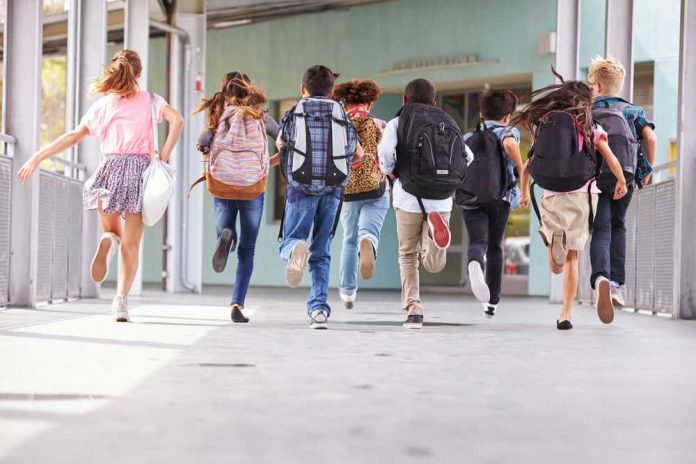 shutterstock_388660693 Children running with backpacks outside a school building.
