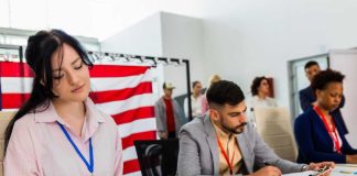People seated at a table filling out forms in a bright office