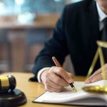 Can This NEW LAW REALLY Protect These WOMEN? Lawyer writing in a legal document beside gavel and scales