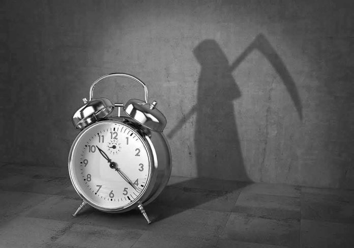 shutterstock_1065322040 alarm clock with grim reaper shadow
