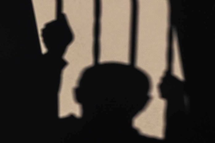 Shadow of a person gripping jail bars