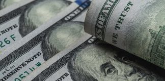 U.S. 100-dollar bills with one note rolled over Benjamin Franklin portrait