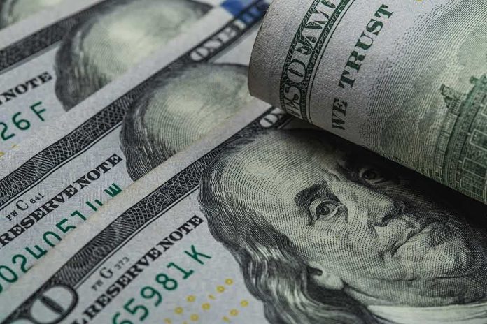 U.S. 100-dollar bills with one note rolled over Benjamin Franklin portrait