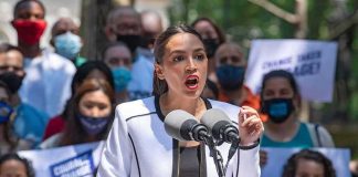 Viral Clip Sparks NEW AOC War Woman speaking at outdoor rally behind microphones