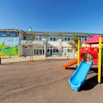 Playground with colorful slide in front of a school building
