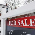 For sale sign in front of a house in winter