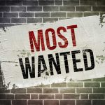 A weathered poster displaying the words MOST WANTED on a brick wall