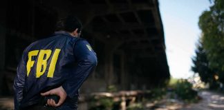 FBI agent stands under an overpass holding a radio