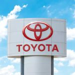 Toyota dealership sign with red logo against blue sky
