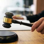 Judge's hand holding a gavel over a sound block