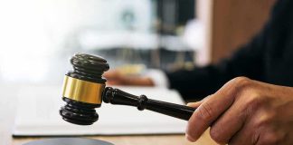 Judge's hand holding a gavel over a sound block