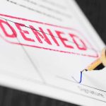 Fountain pen signing a form marked denied
