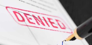 Fountain pen signing a form marked denied