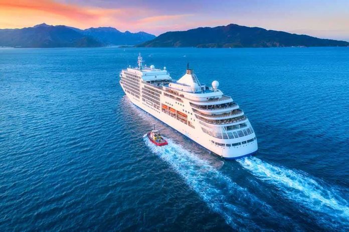 Cruise ship sailing at sunset near mountainous coastline