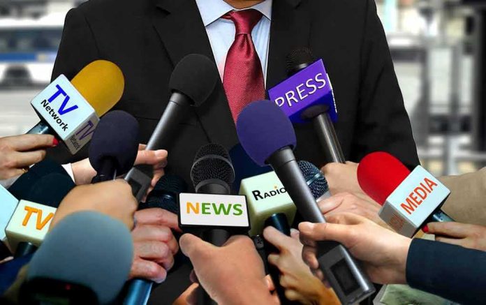 Press microphones surround a suited spokesperson