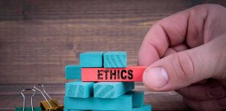 Hand holding a red block labeled ethics above teal blocks