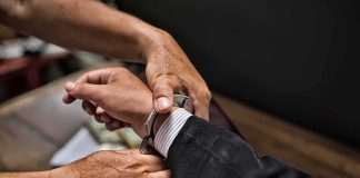 SHOCKING — Congressional Candidate ARRESTED! hands placing handcuffs on a suited person's wrists