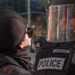 protester faces police officer in riot gear
